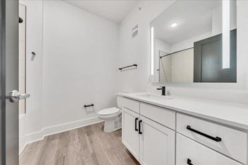 A white bathroom with a toilet, sink, and mirror.